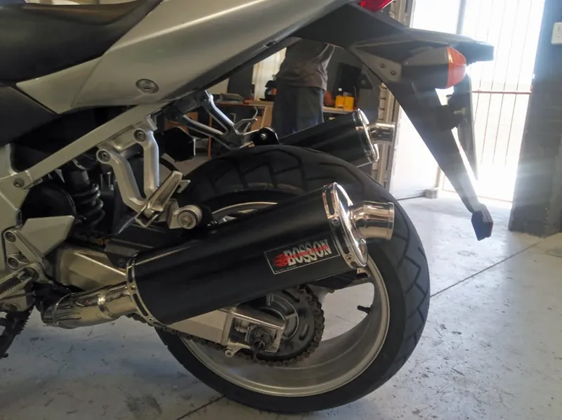 Black BOSSON canister with a polished tip on a silver motorcycle
