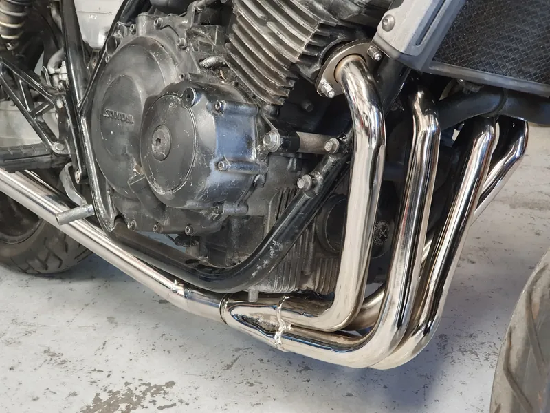 Polished stainless four-into-one headers on a Honda four-cylinder engine