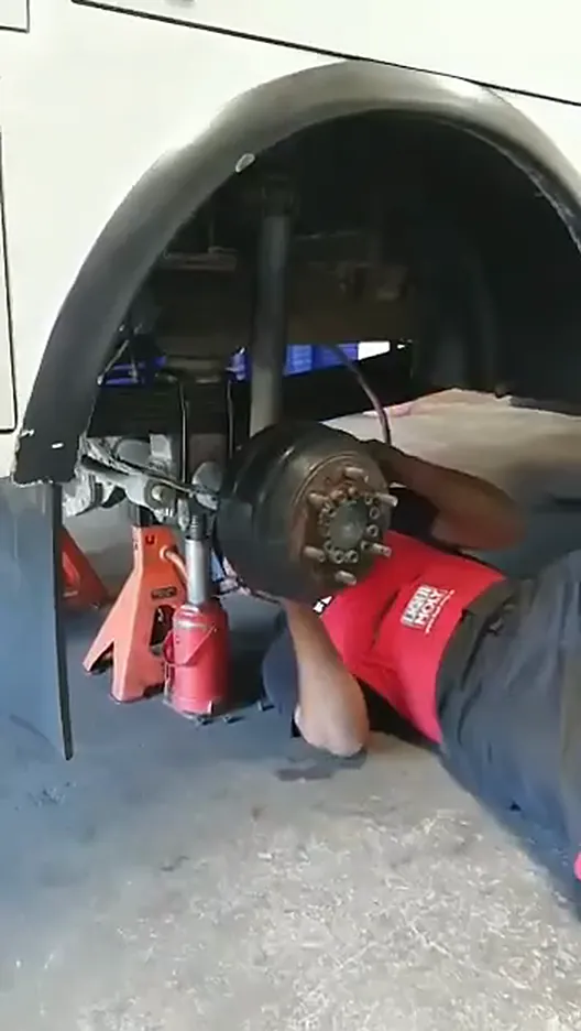 Mechanic lying under the vehicle working on the hub, on axle stands