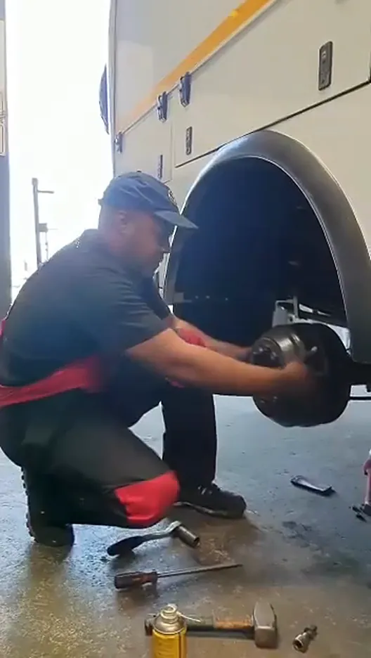 Mechanic lifting the brake drum and hub off the axle